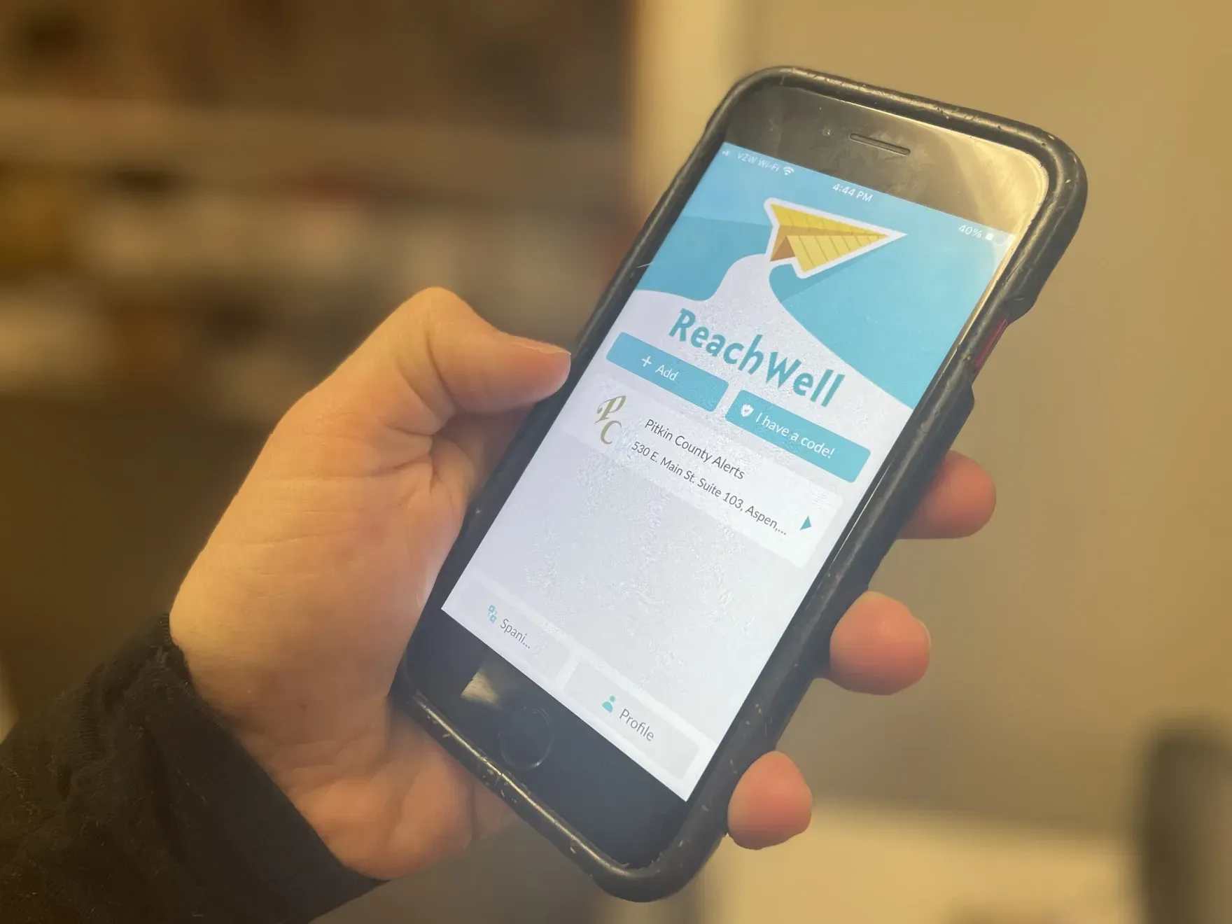 A person is holding a cell phone that says reachwell on the screen