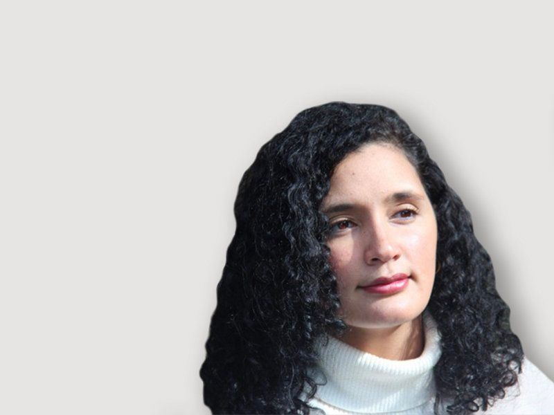 Woman with curly black hair, wearing a white turtleneck, looking off-camera.