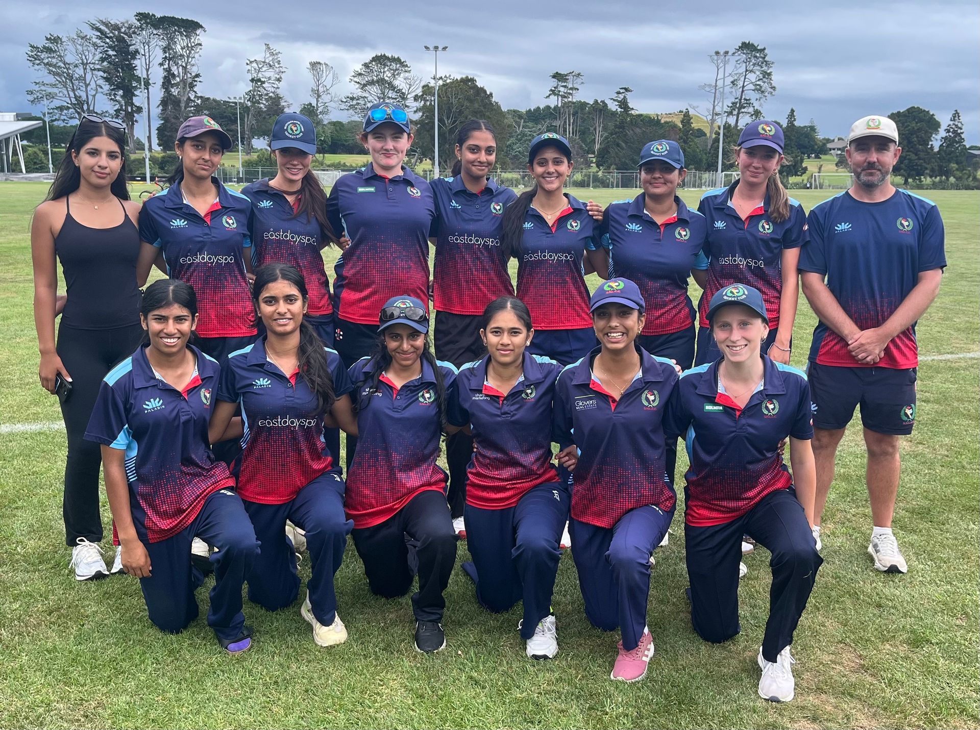 Sports team posing outdoors in matching navy and red uniforms on a grassy field