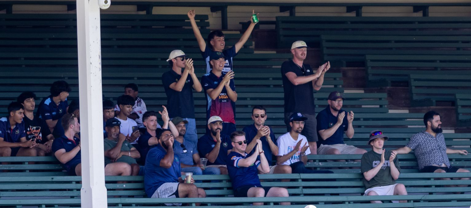 Spectators in green bleachers cheering and waving at a sports event