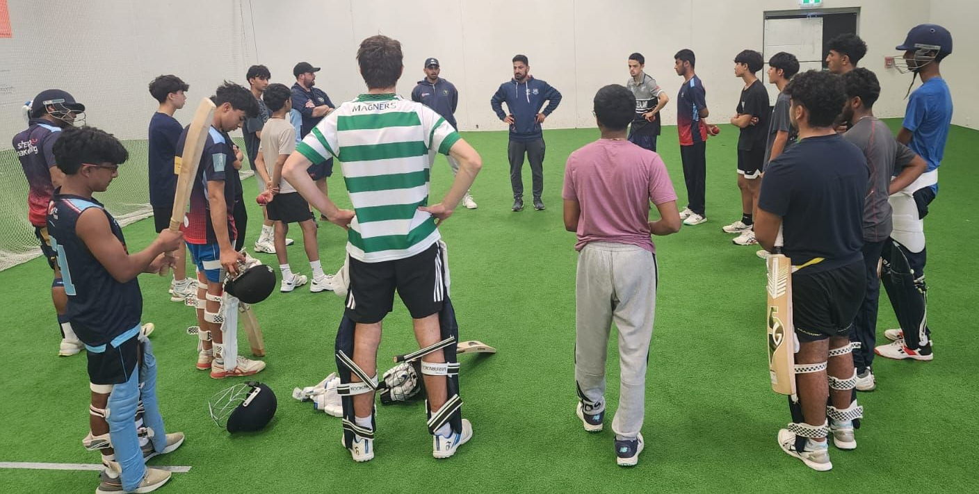 Group of people standing on a sports field with prosthetic legs, listening to an instructor in the center