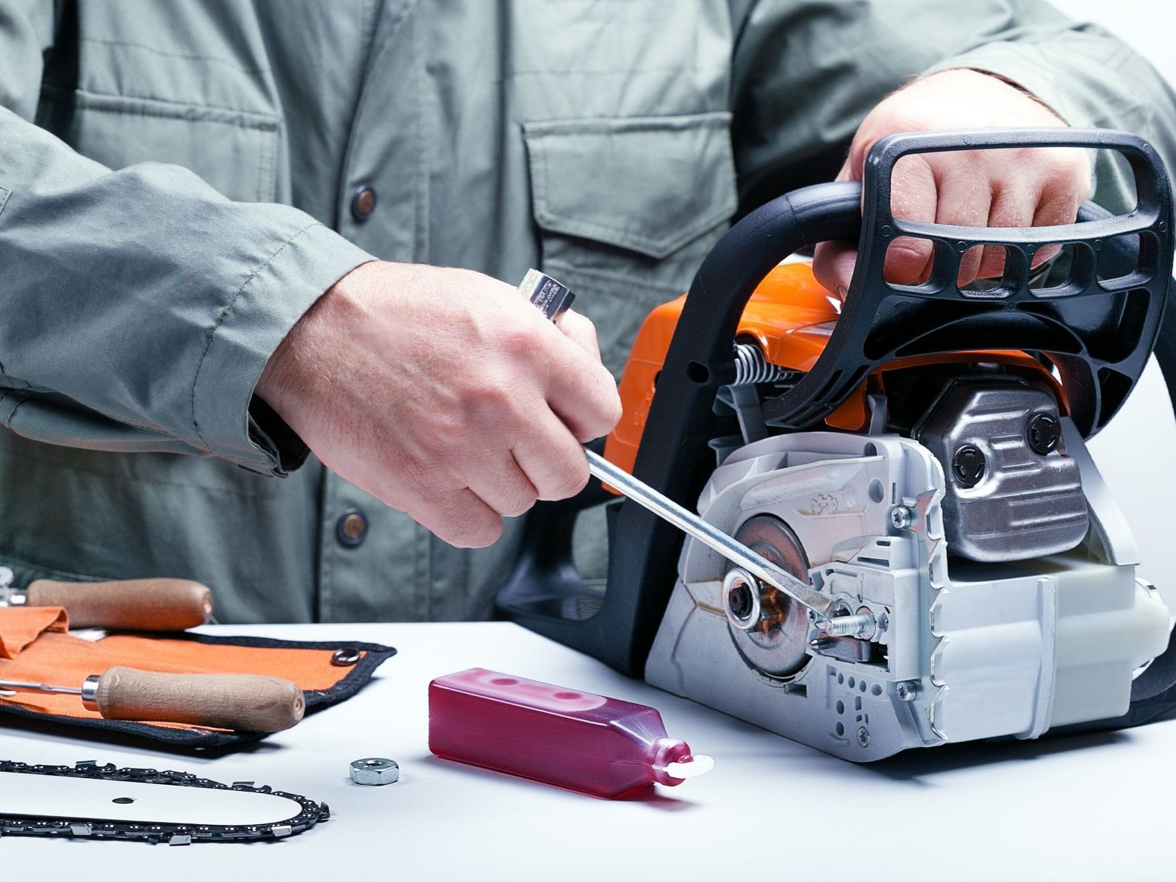 a man is fixing a chainsaw with a wrench