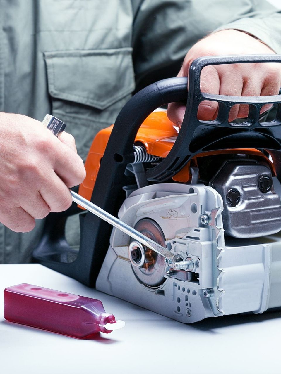 a man is fixing a chainsaw with a wrench