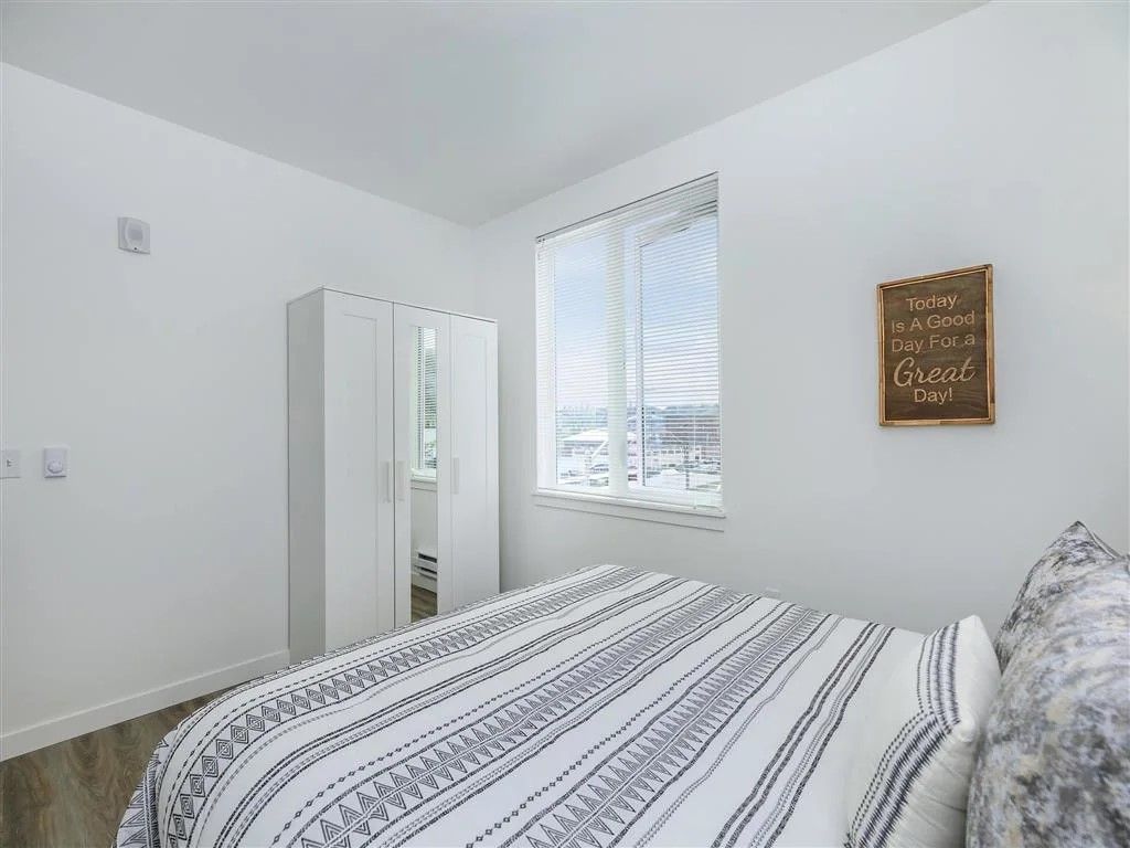 White bedroom with bed, closet, window, and decorative sign.