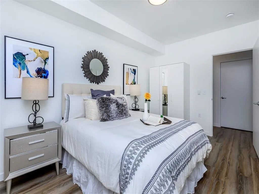 Bedroom with a bed, nightstand, artwork, and white walls.