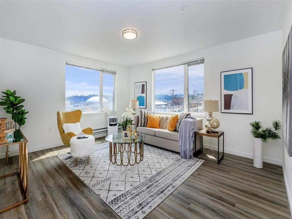 Living room with a sofa, armchair, coffee table, and large windows with a snowy outdoor view.