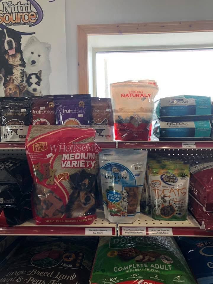 Pet store shelf stocked with assorted dog food bags and cans, including red and blue packaging