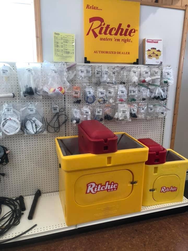 Ritchie cleaning supplies display with yellow bins, hoses, and packaged parts on a pegboard wall