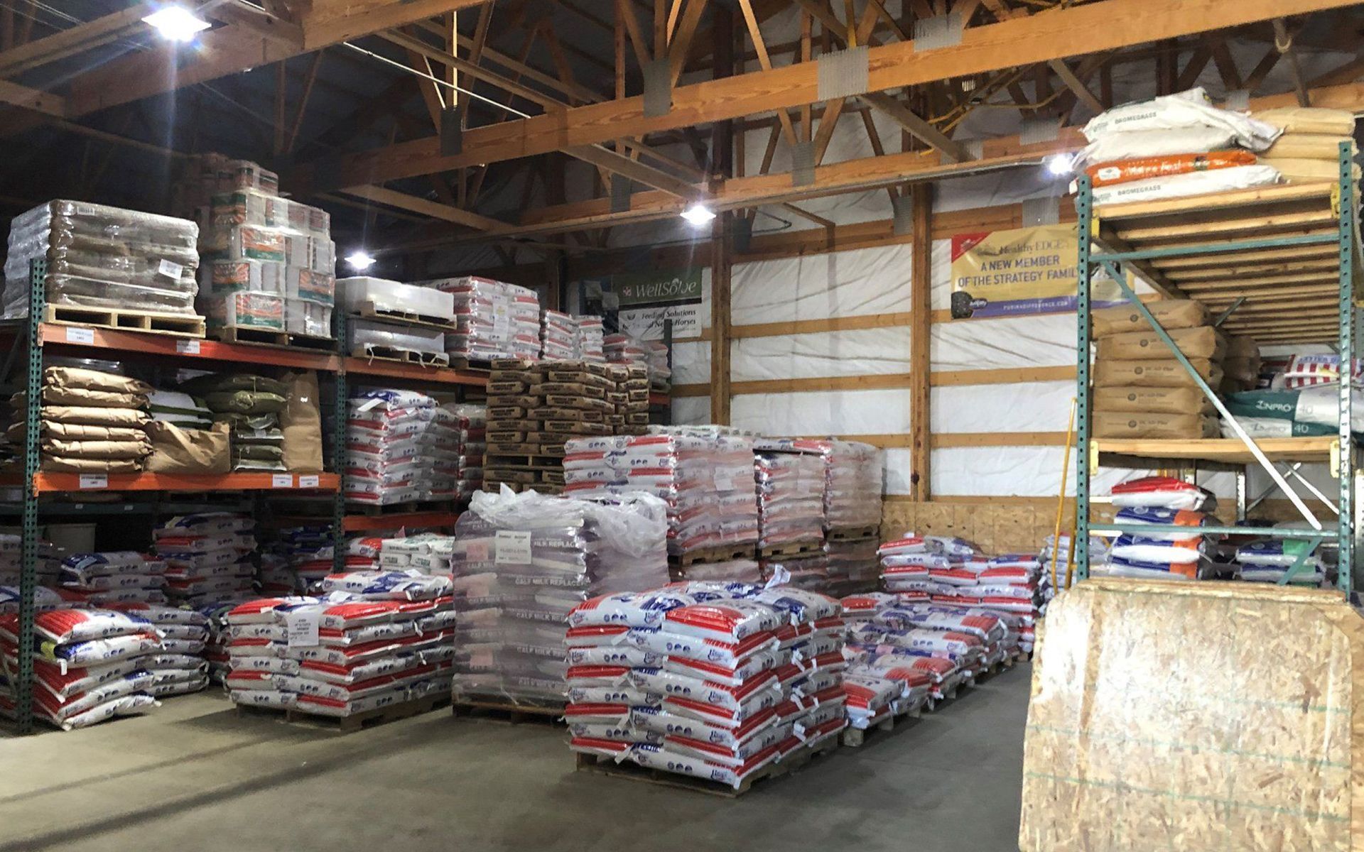 Warehouse interior with stacked bags and pallets of supplies under exposed wooden beams