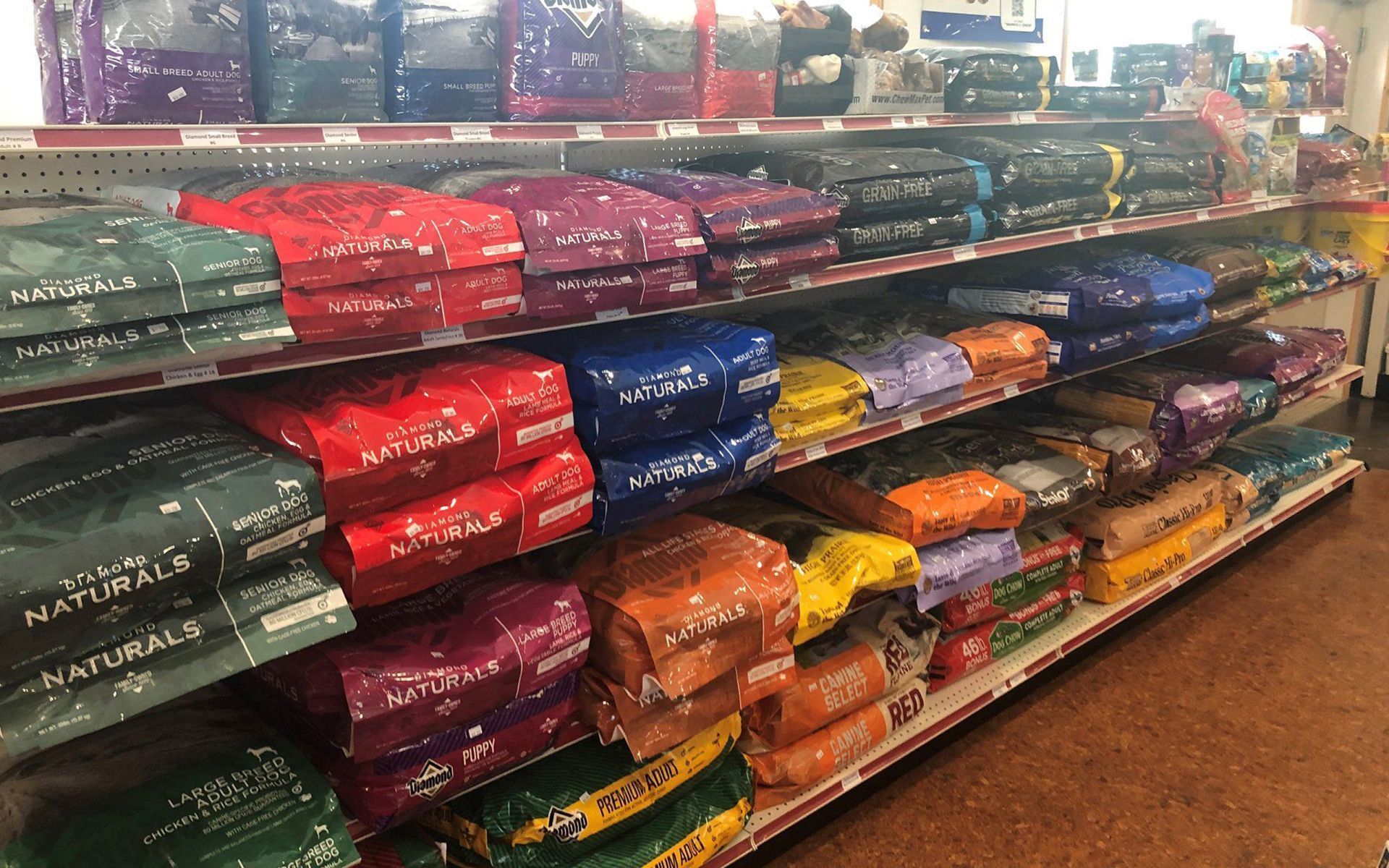 Pet store aisle with stacked bags of pet food in red, blue, orange, and green packages