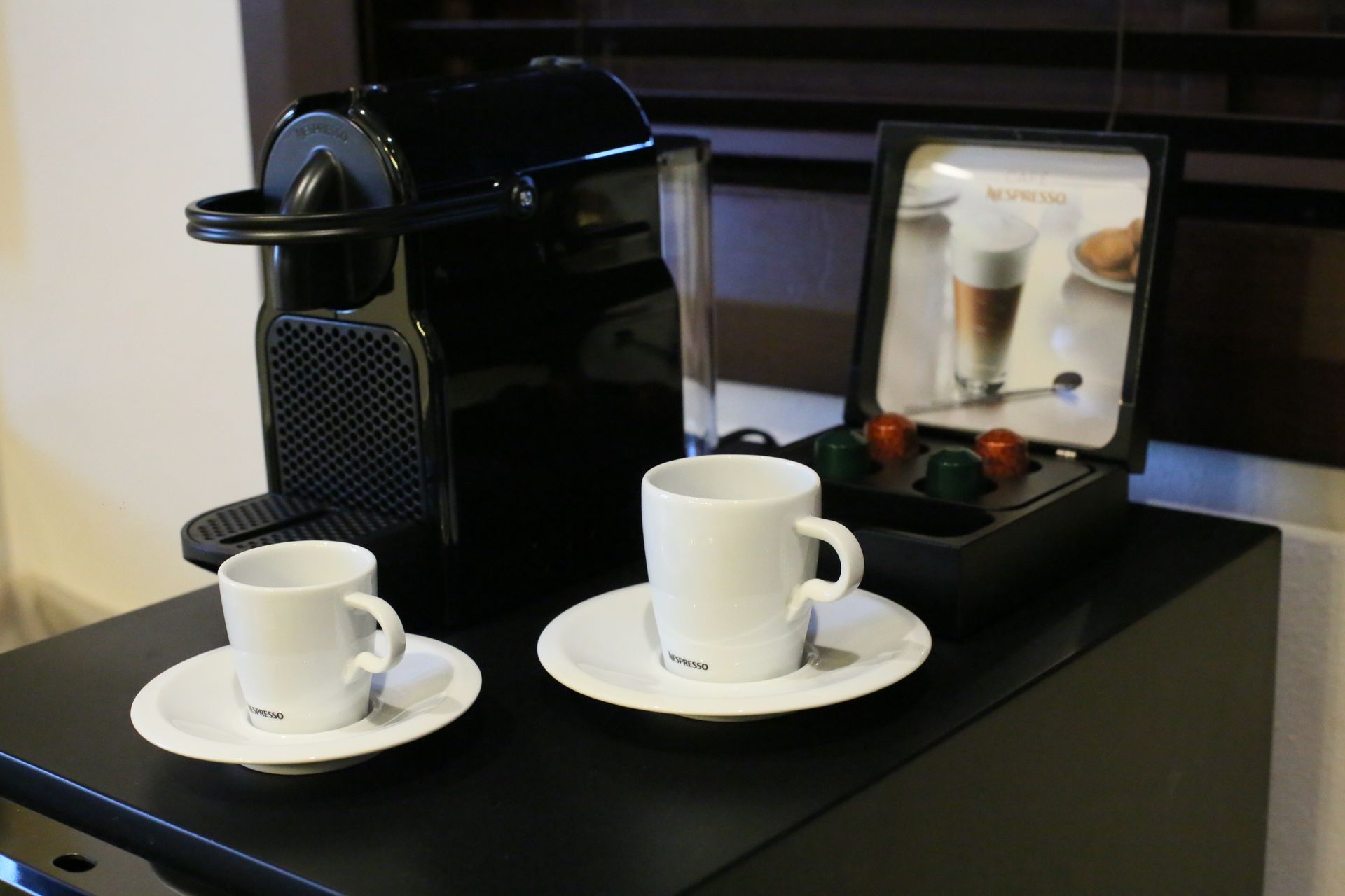 Two cups and saucers on a counter next to a nespresso machine