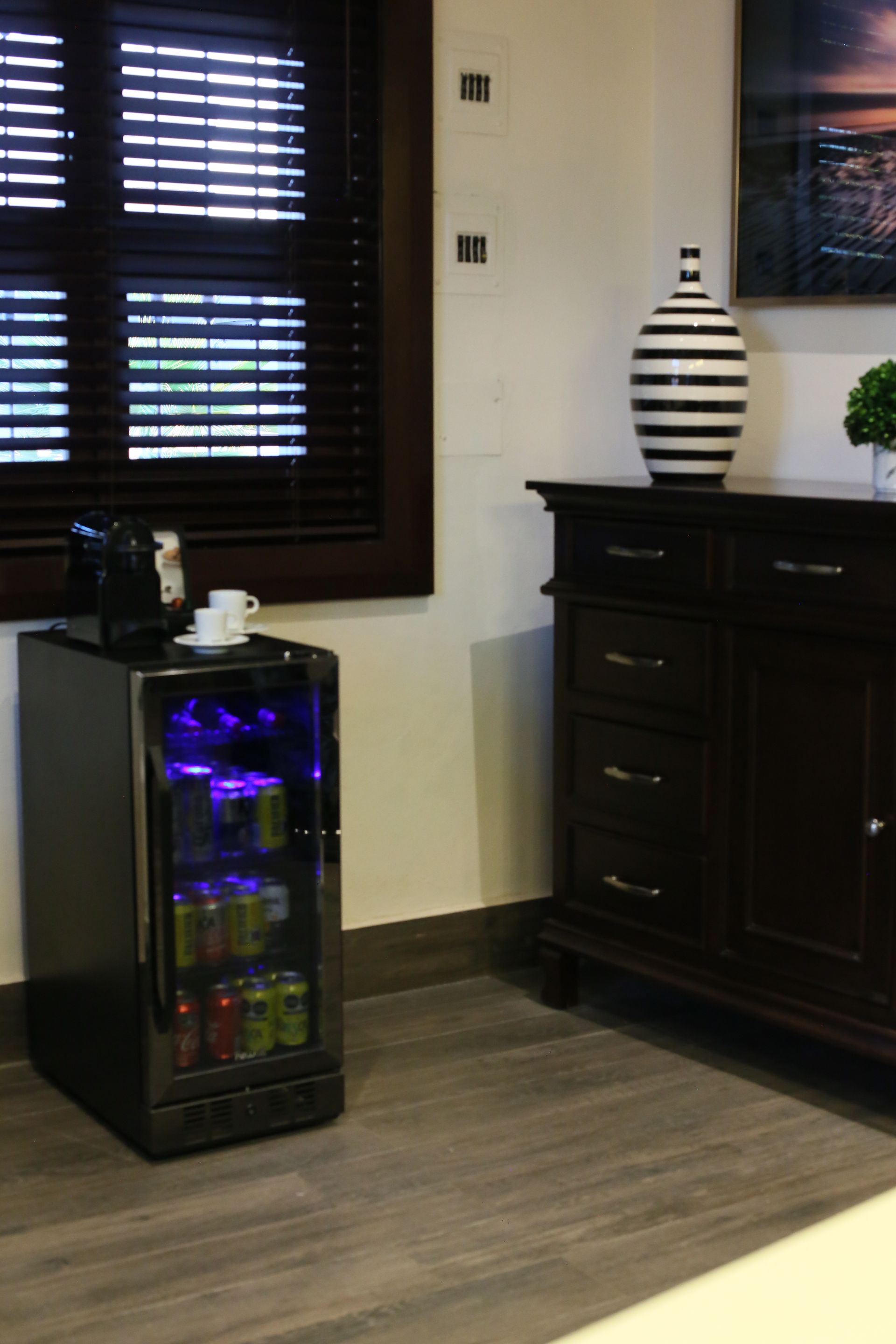 A room with a fridge and a window with blinds