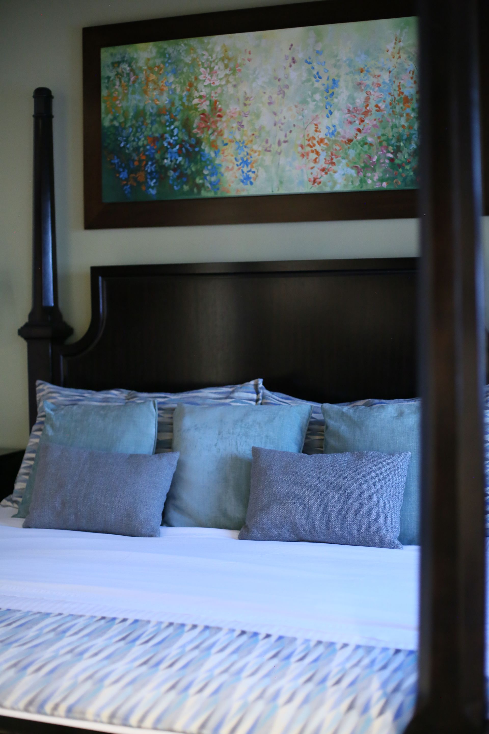 There is a painting on the wall above the bed.