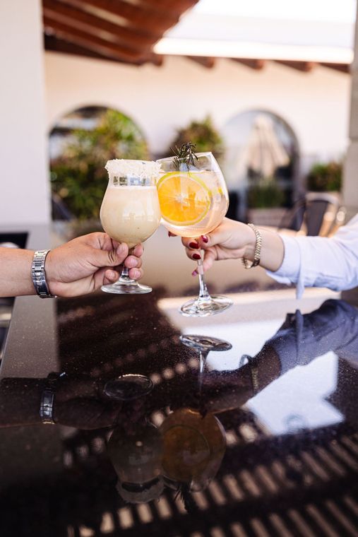 Un hombre y una mujer brindan con bebidas en un bar.