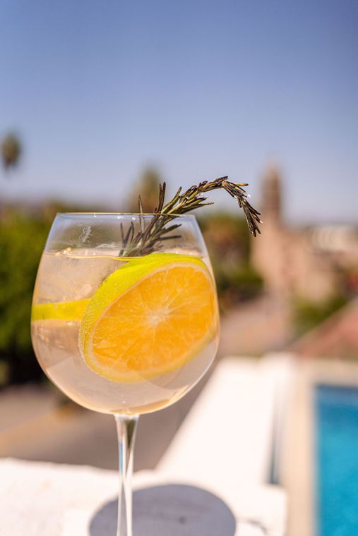 Un primer plano de un vaso de gin tonic con una rodaja de naranja encima.