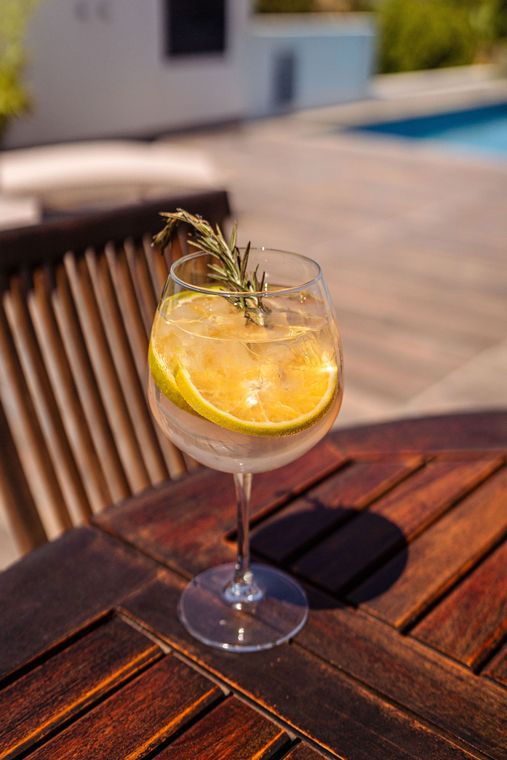 Un vaso de gin tonic con una rodaja de limón sobre una mesa de madera.