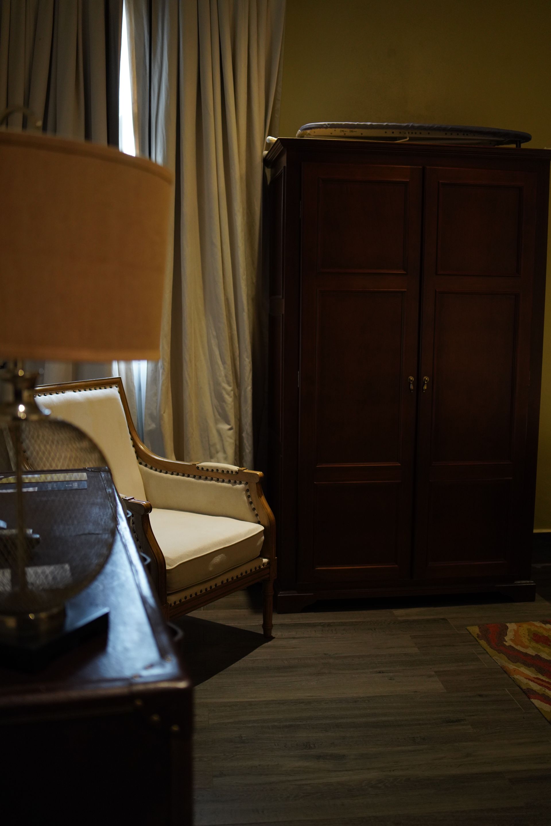 A room with a chair a lamp and a wardrobe