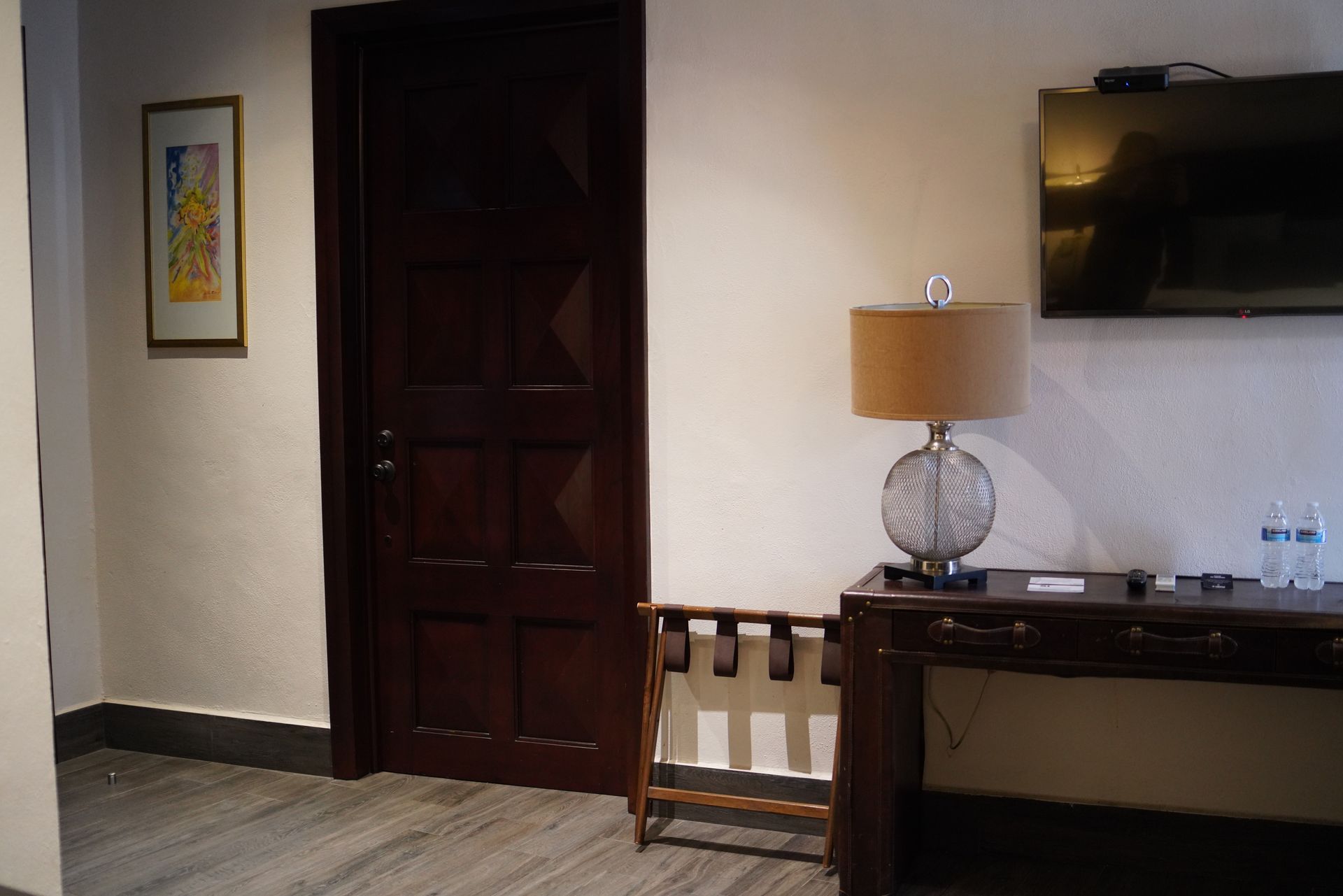 A hotel room with a desk and a lamp