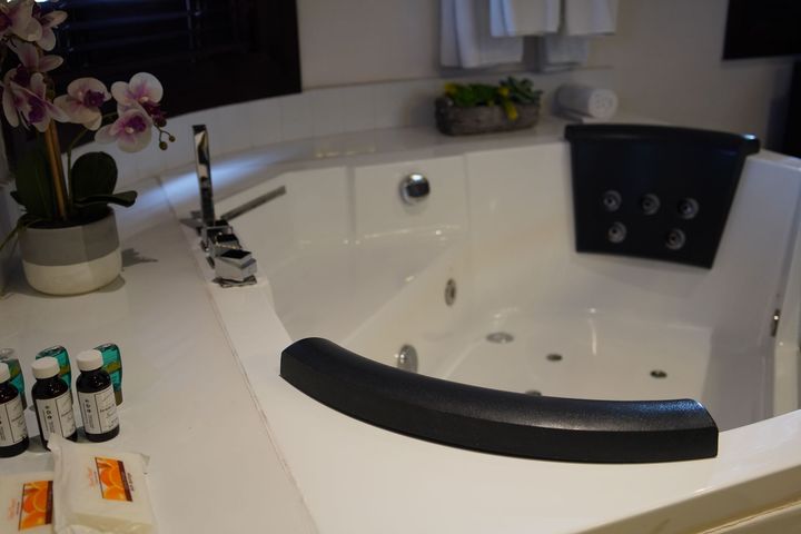 Una bañera de hidromasaje en un baño al lado de un jarrón con flores.