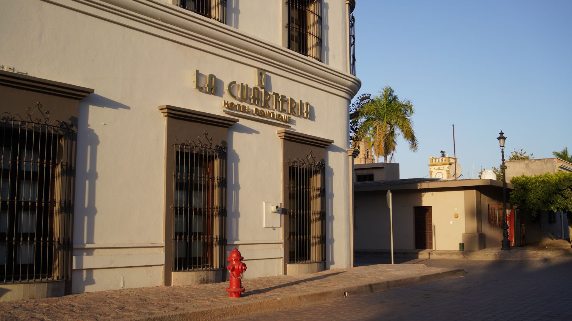 Un edificio blanco con una boca de incendios roja delante.