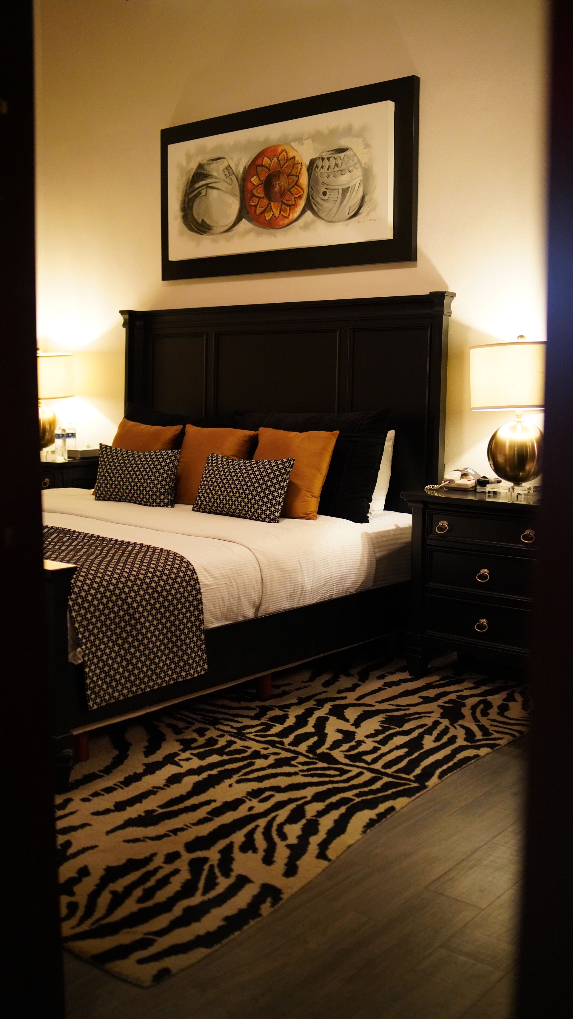 A bedroom with a large bed and a zebra print rug.