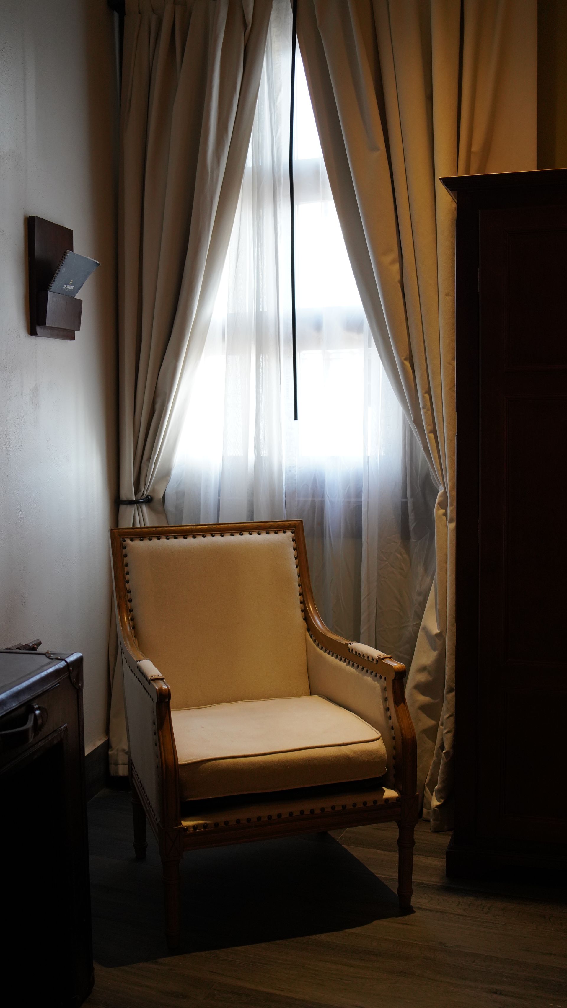 A chair is sitting in front of a window in a dark room.