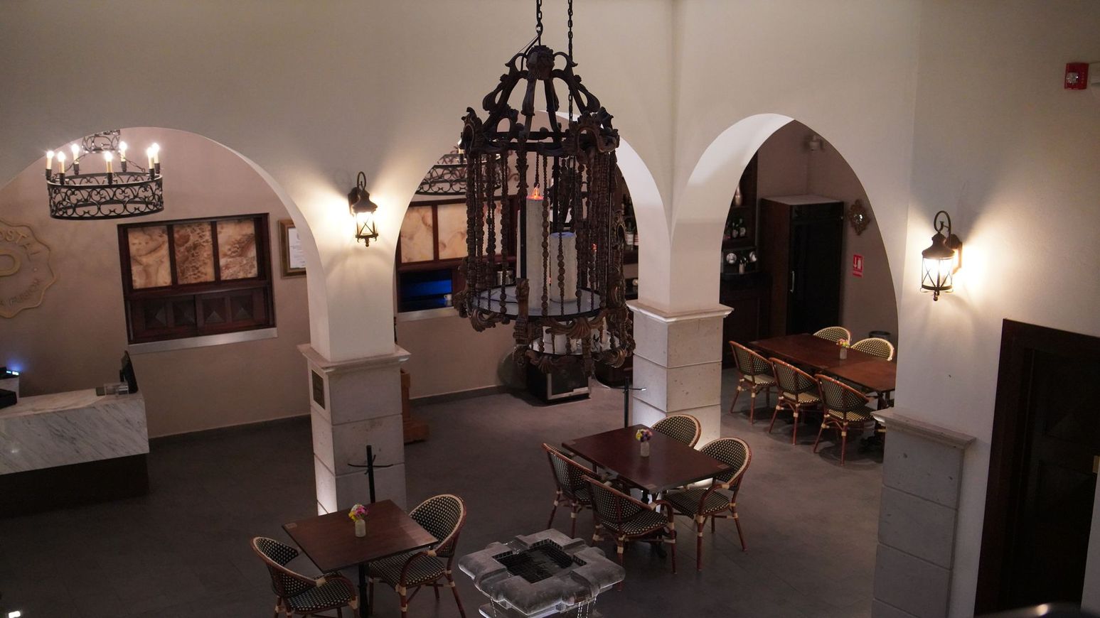 Una gran sala con arcos, mesas y sillas.