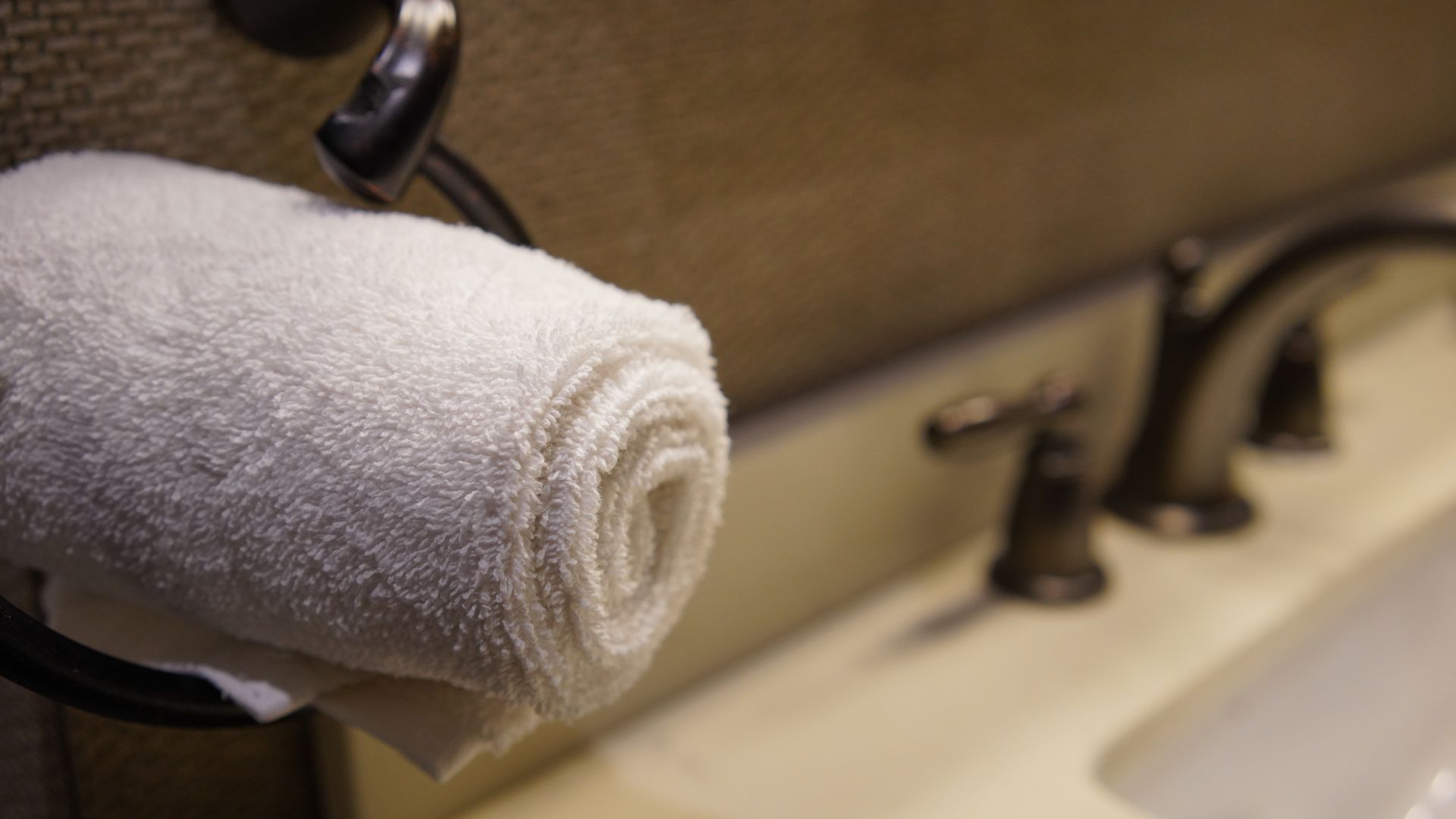 A white towel is hanging on a towel rack in a bathroom next to a sink.