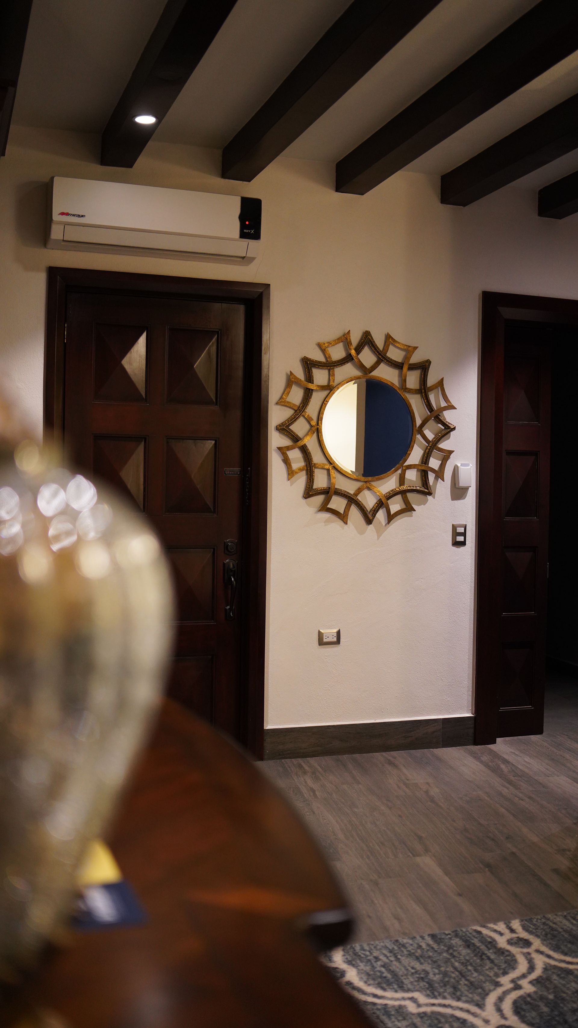 A room with a mirror on the wall and a vase on the table.