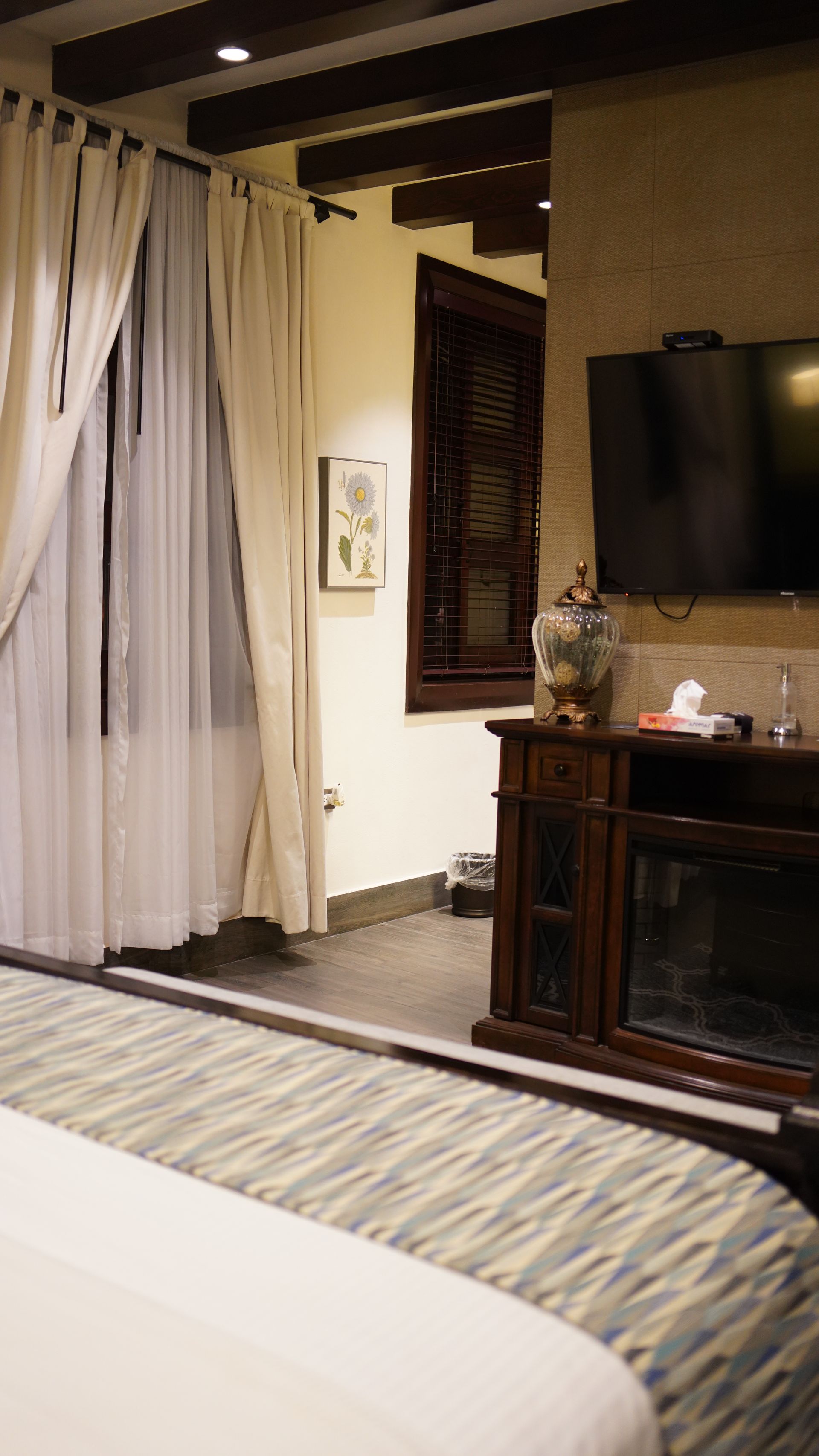 A hotel room with a bed , television and fireplace.