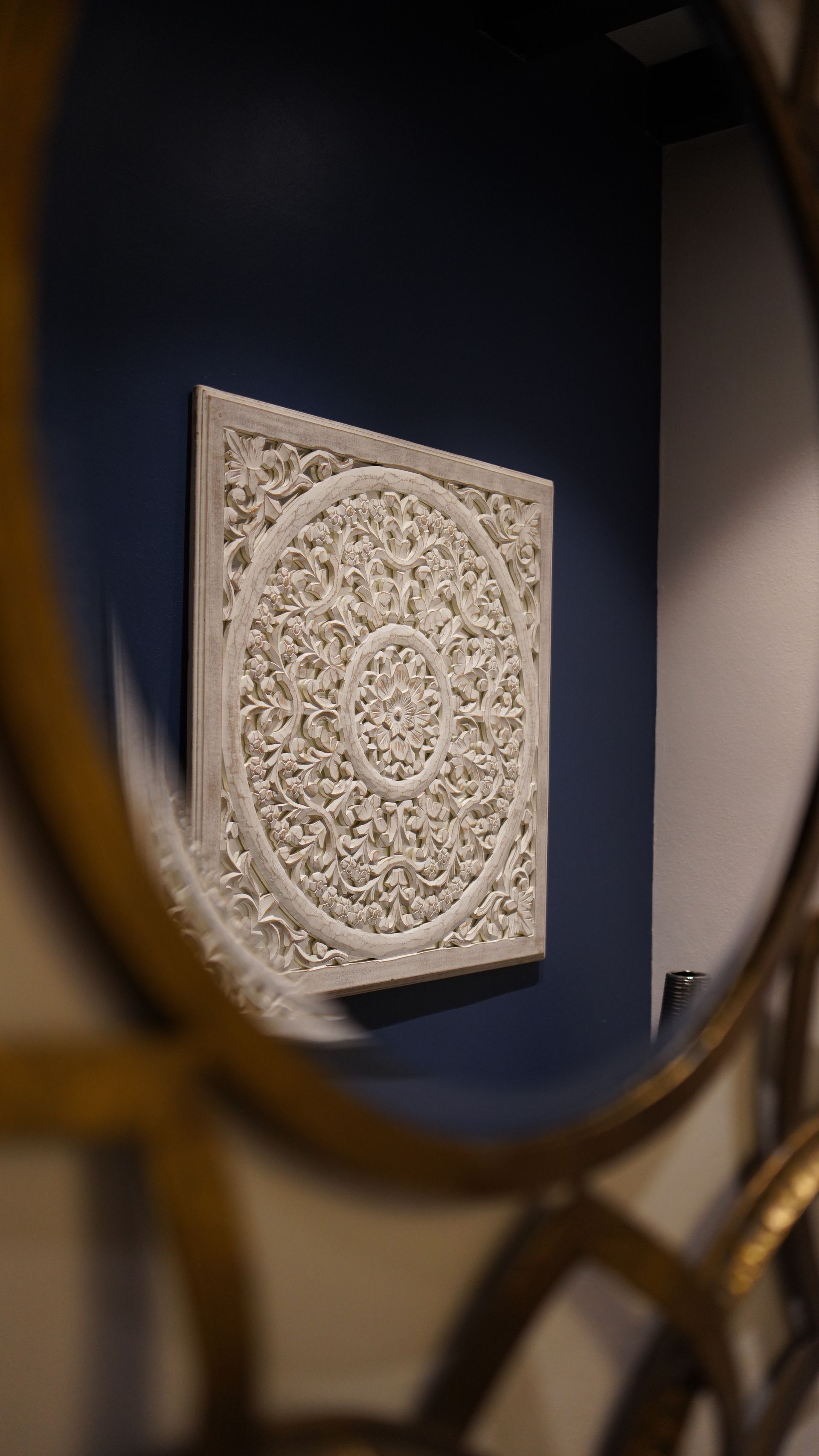 A square painting is hanging on a wall next to a mirror.
