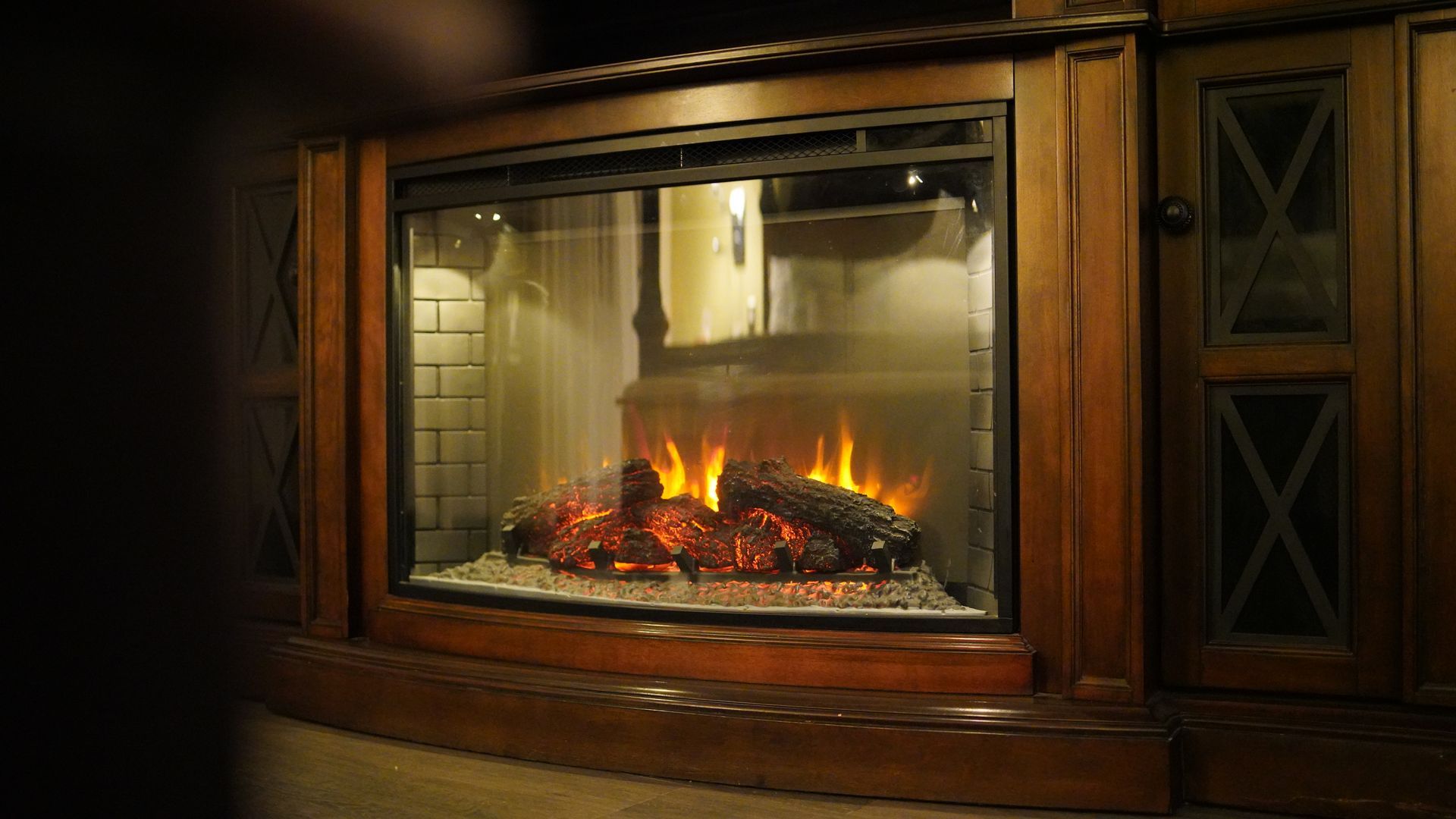 A fireplace with a lot of logs in it is lit up at night.