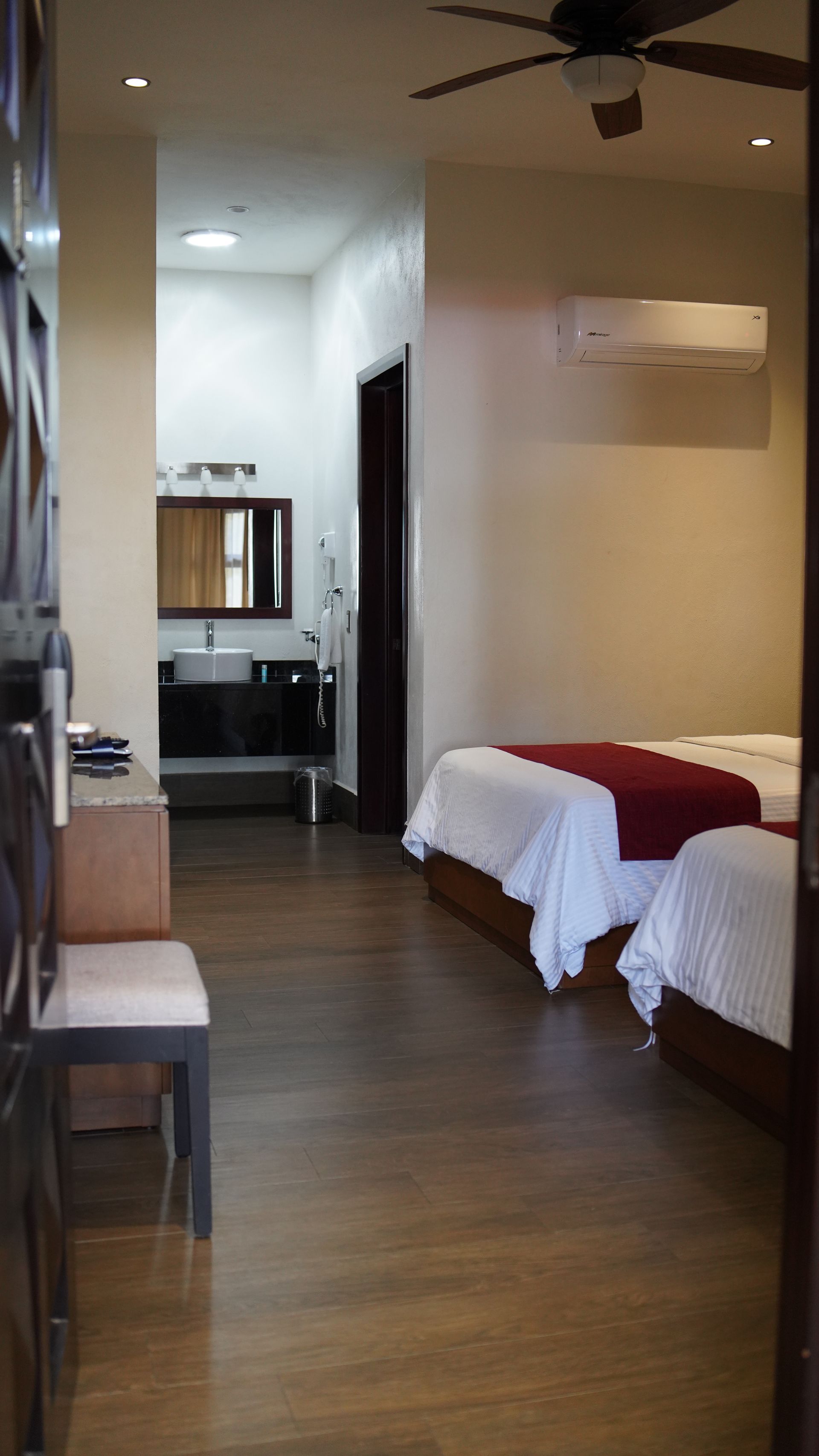 A hotel room with two beds and a ceiling fan.