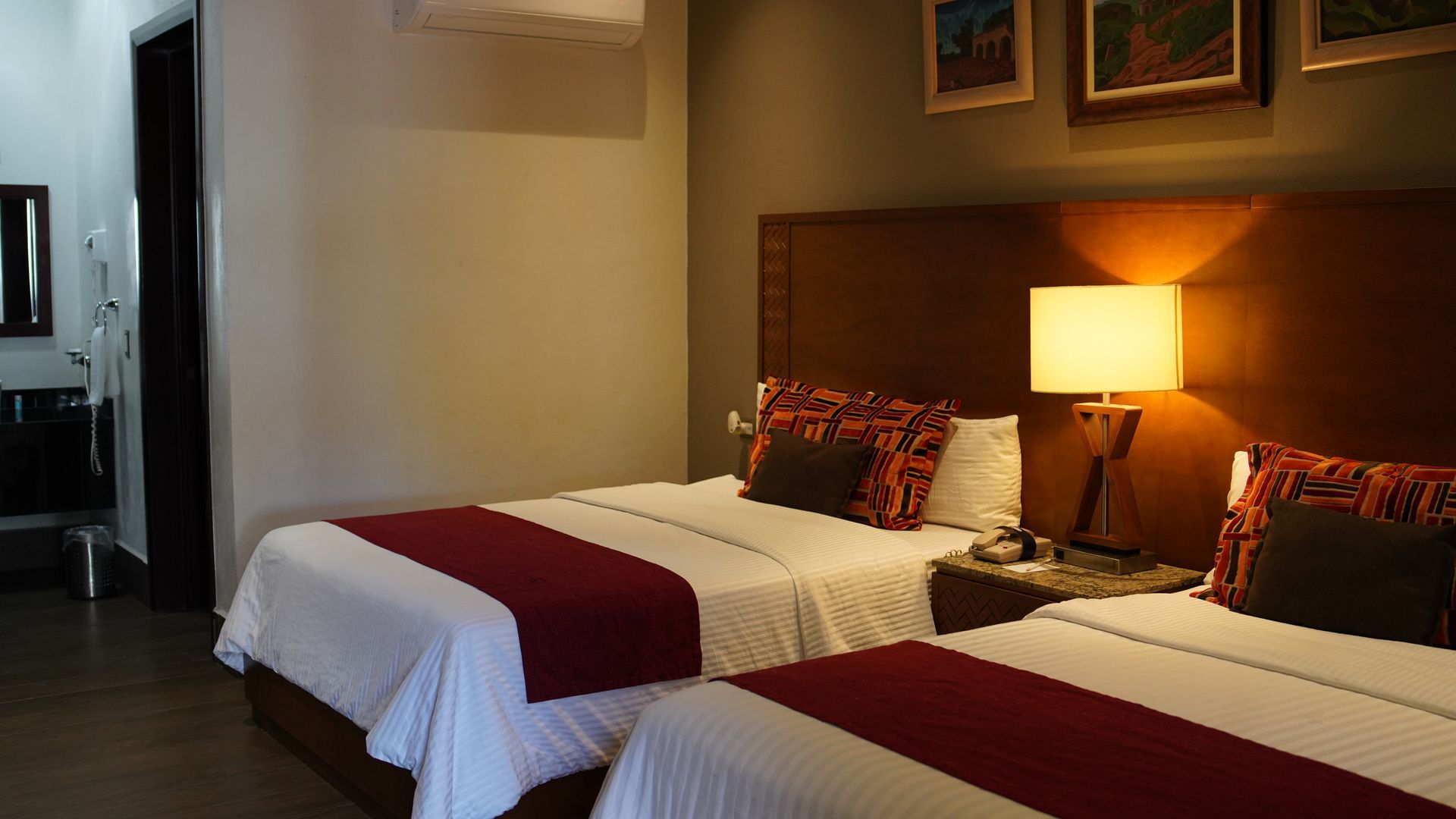 A hotel room with two beds and a lamp.