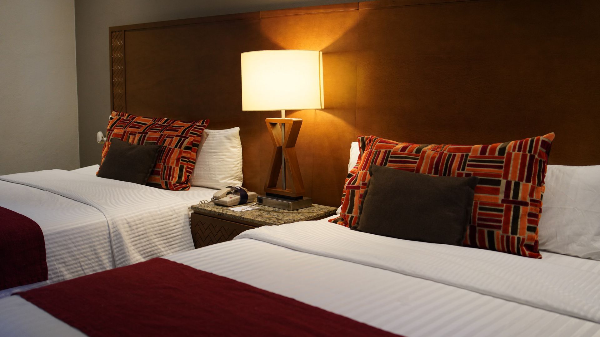 A hotel room with two beds and a lamp.