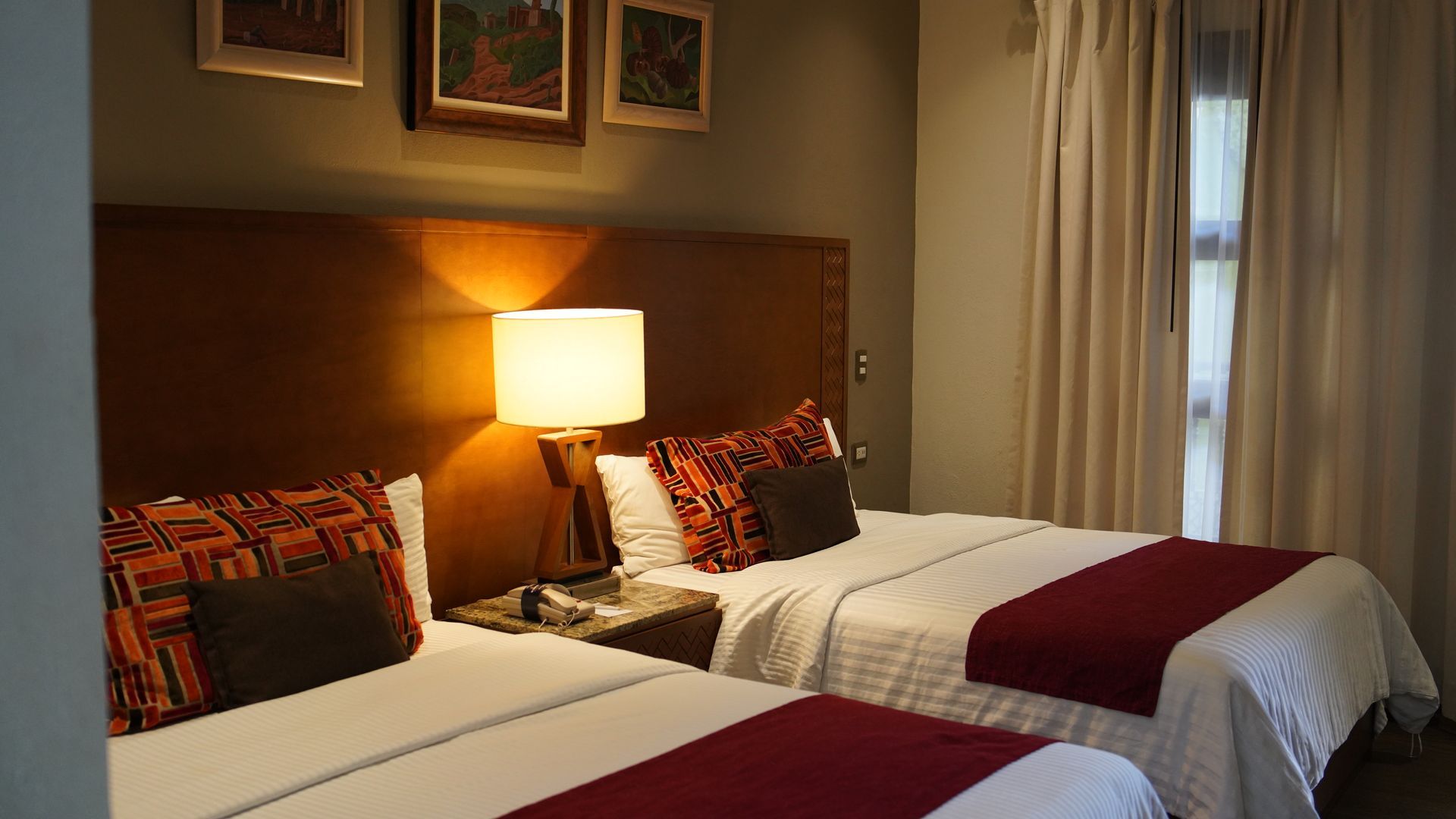 A hotel room with two beds and a lamp.