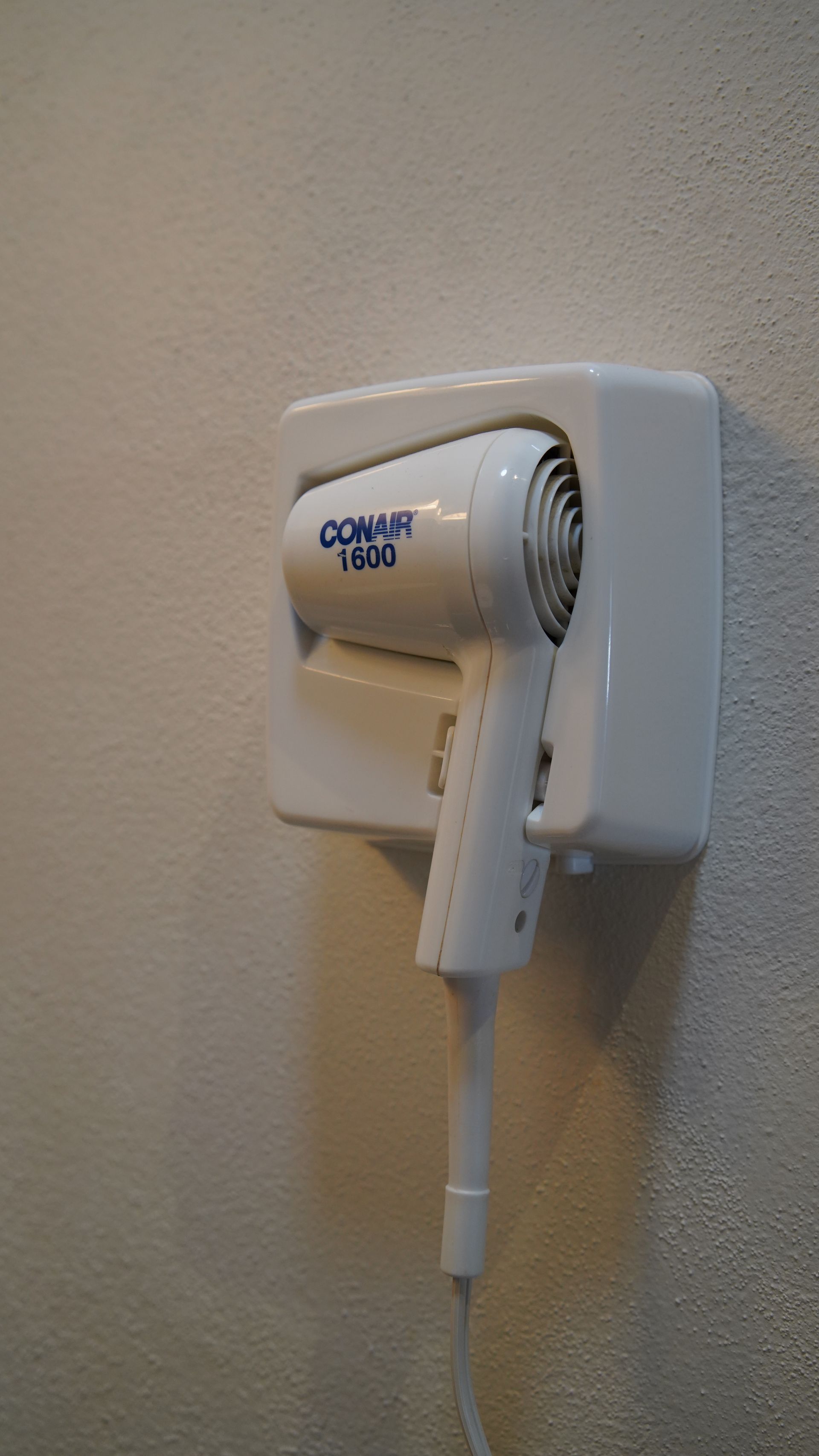 A hair dryer is hanging on a wall in a bathroom.