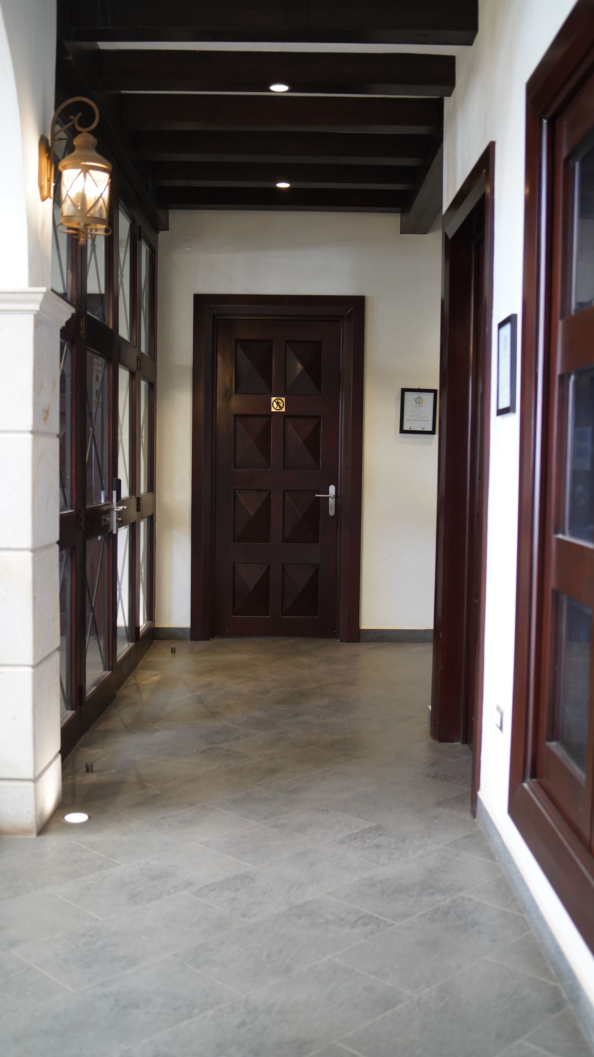 A hallway with a door and a lamp on the wall