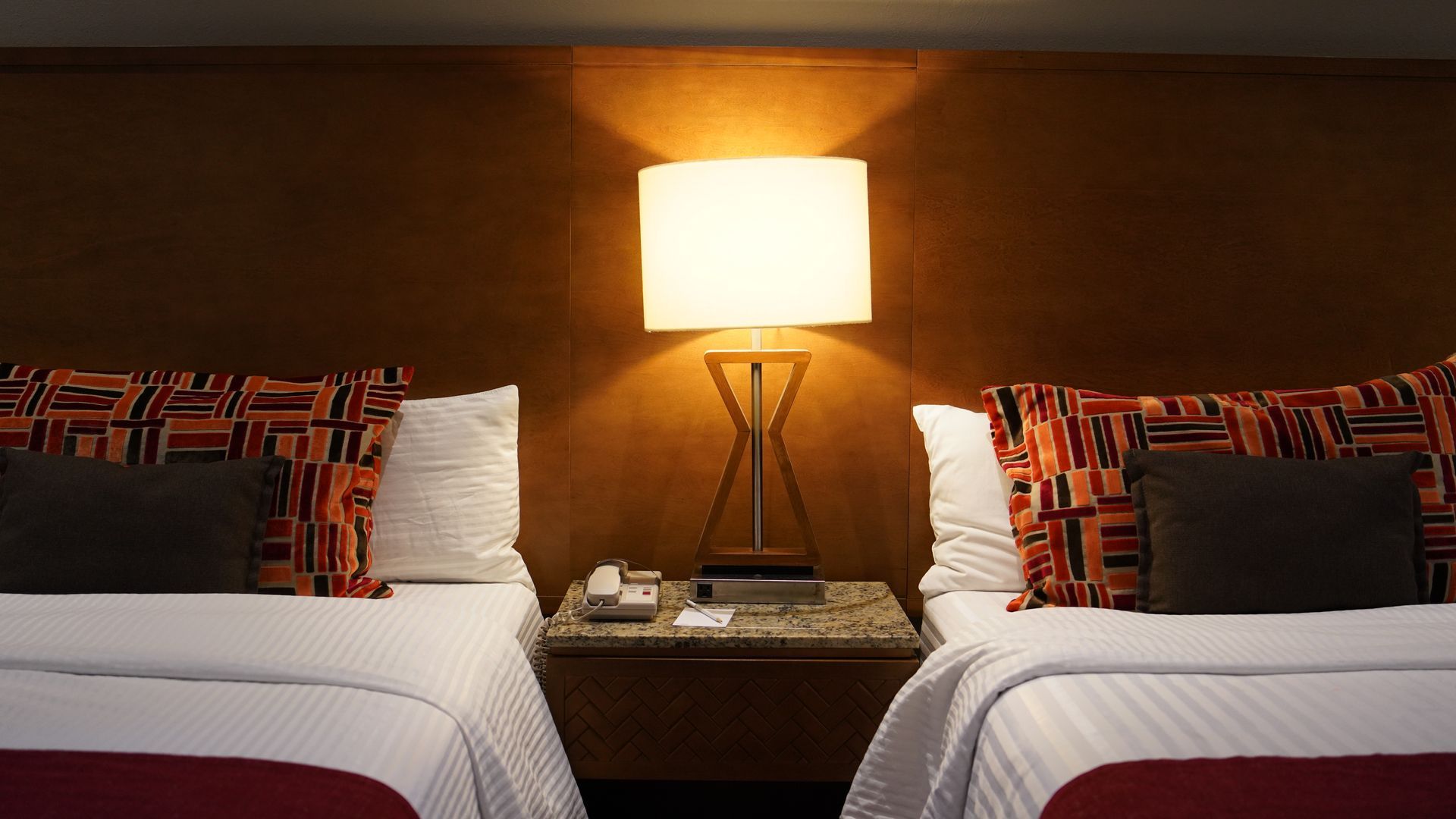 A hotel room with two beds and a lamp.