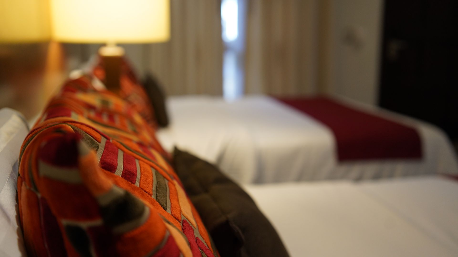 A hotel room with two beds and a lamp.