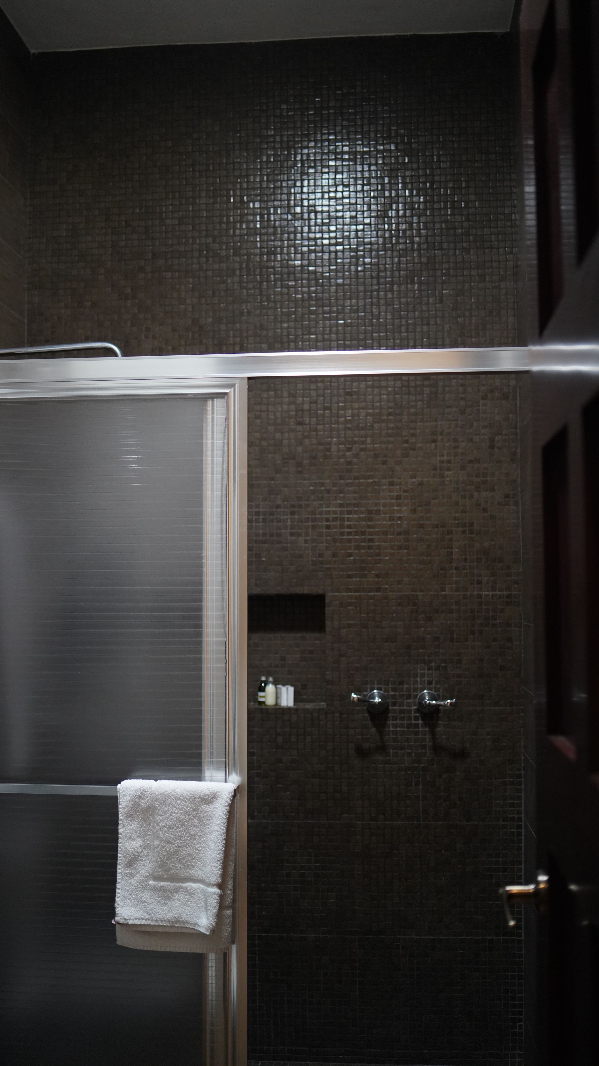 A bathroom with a glass shower door and a towel hanging on the wall.