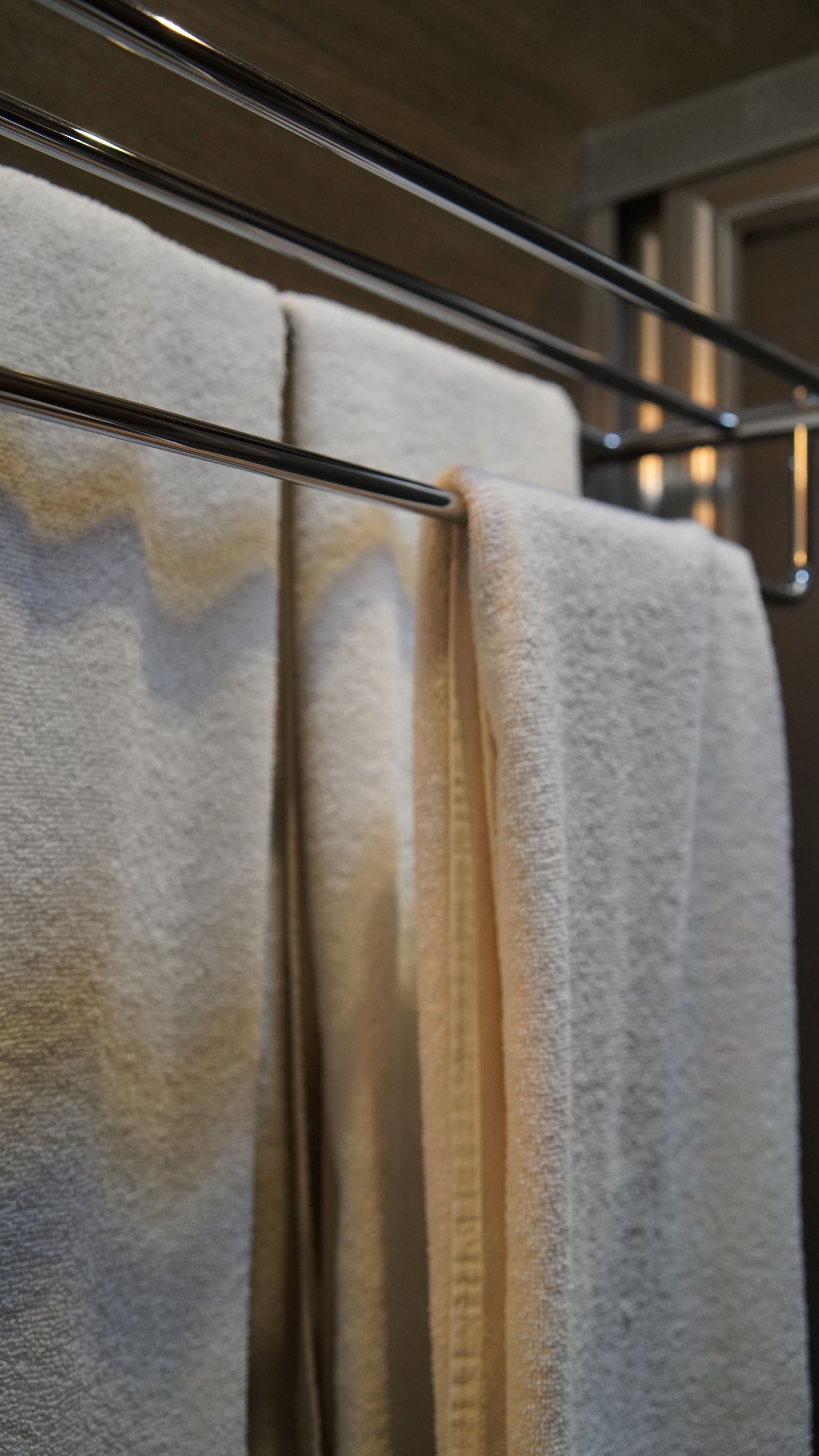 A bunch of towels are hanging on a rack in a bathroom.