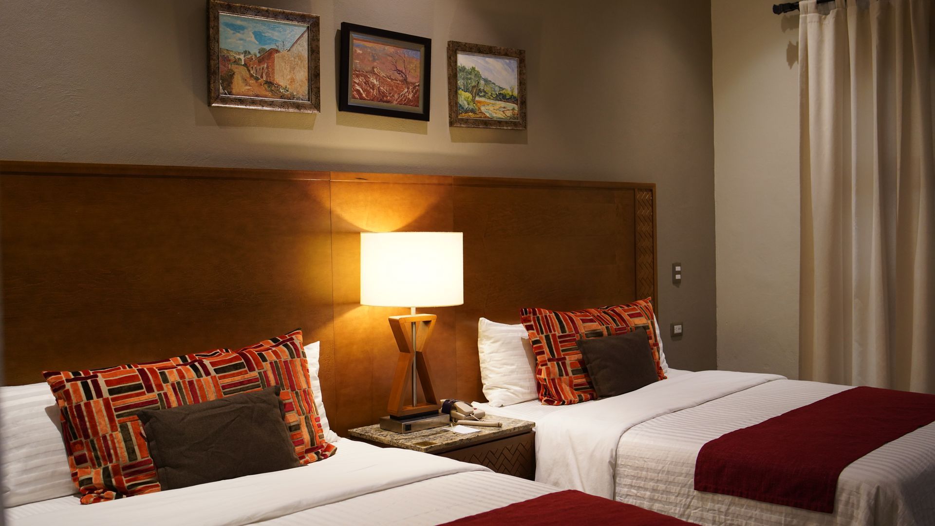 A hotel room with two beds and a lamp