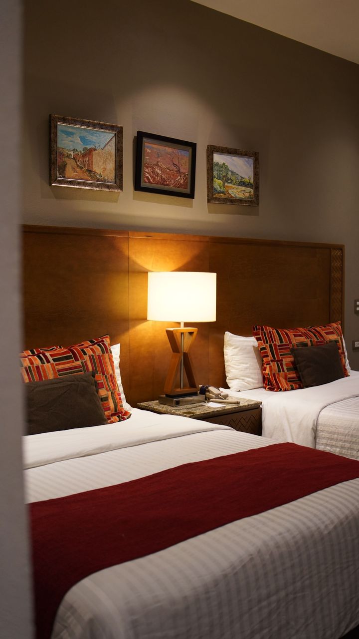 Una habitación de hotel con dos camas y una lámpara.