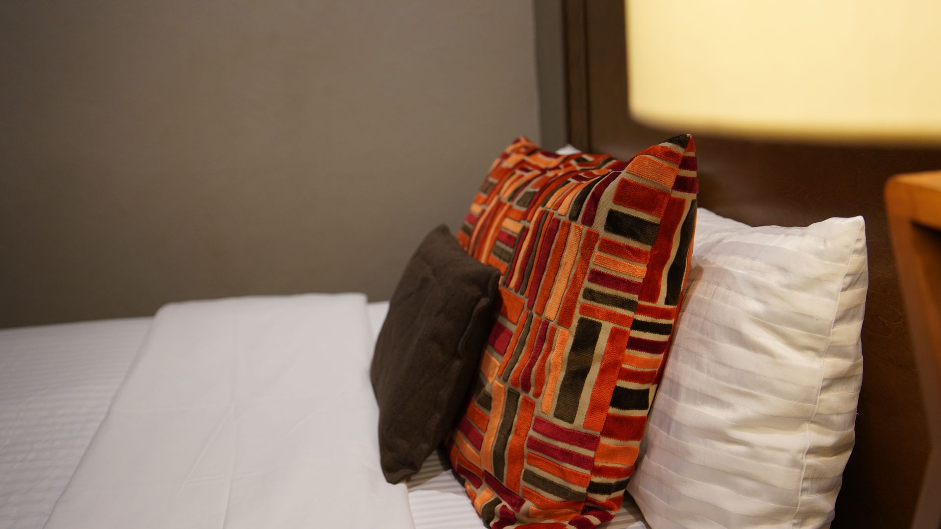 A bed with two pillows and a lamp on it