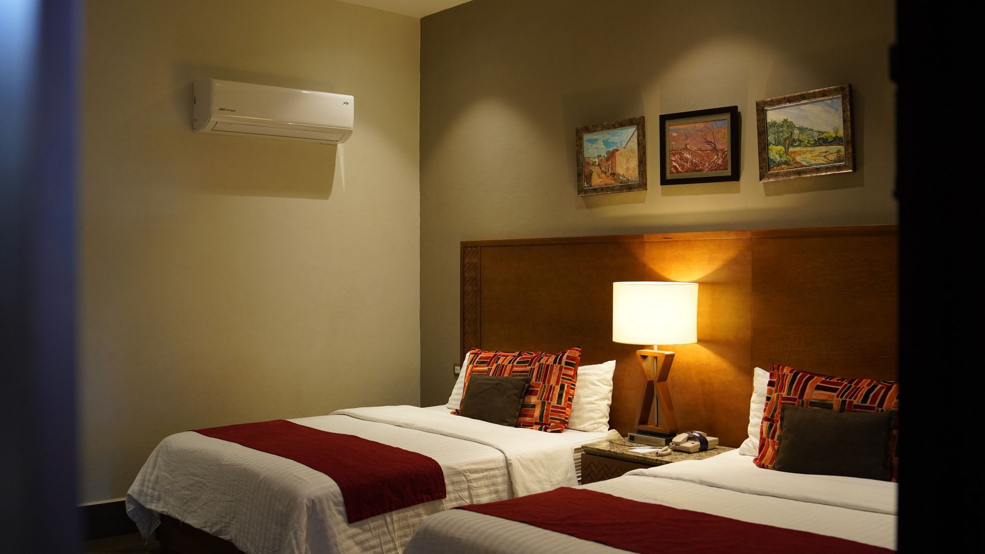 A hotel room with two beds and a lamp.