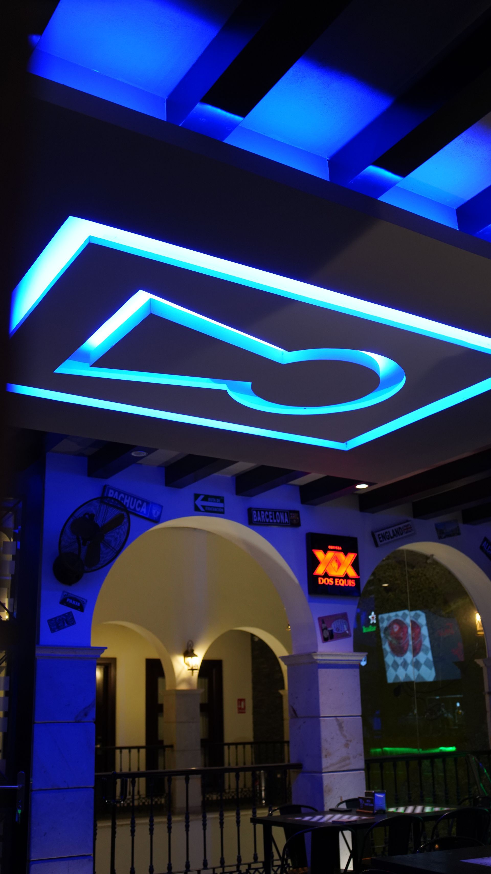 A ceiling with blue lights and a sign that says dos equis