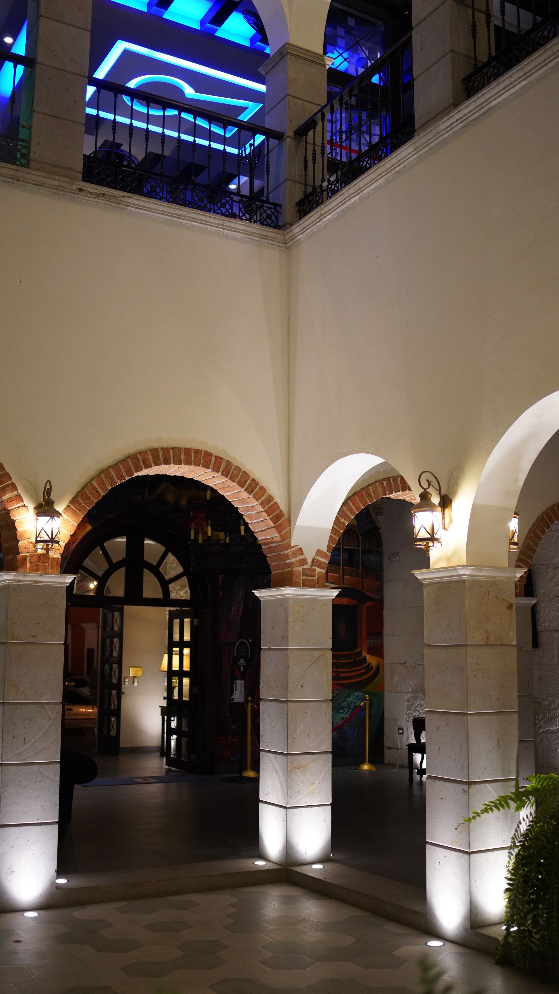 Un edificio con arcos y columnas se ilumina por la noche.