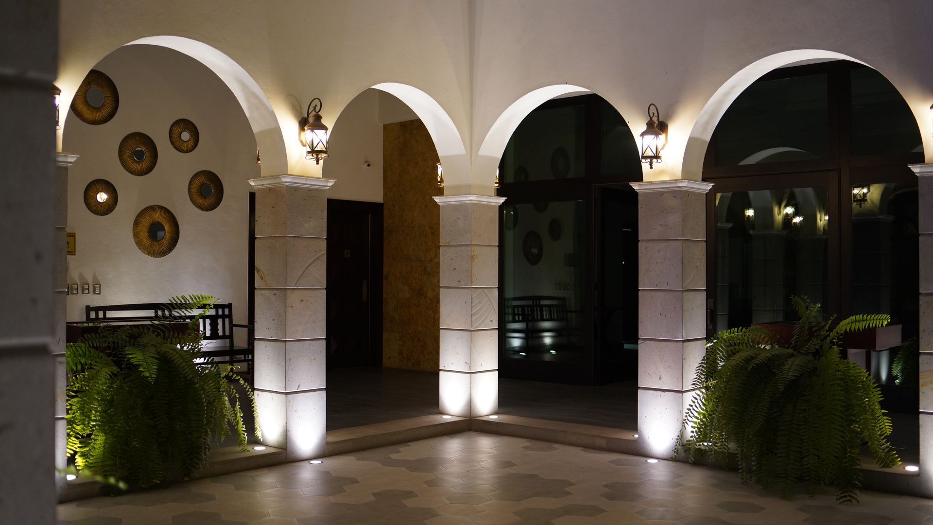 A building with arches and potted plants is lit up at night