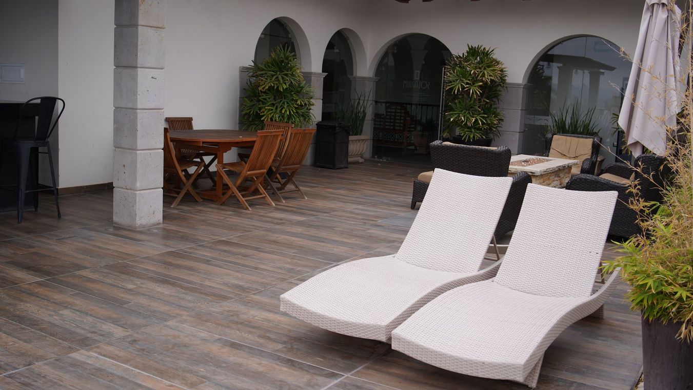 Hay dos sillones blancos sobre una terraza de madera junto a una mesa y sillas.